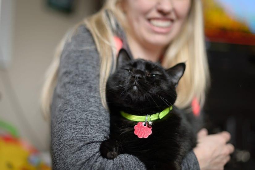 A lady holding a black cat